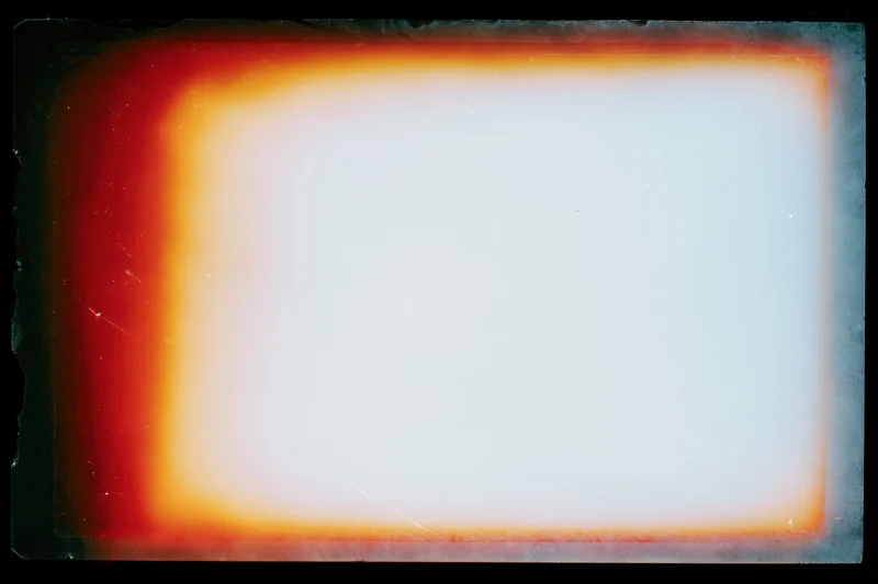 Blank overexposed analog film frame with red-orange light leak border