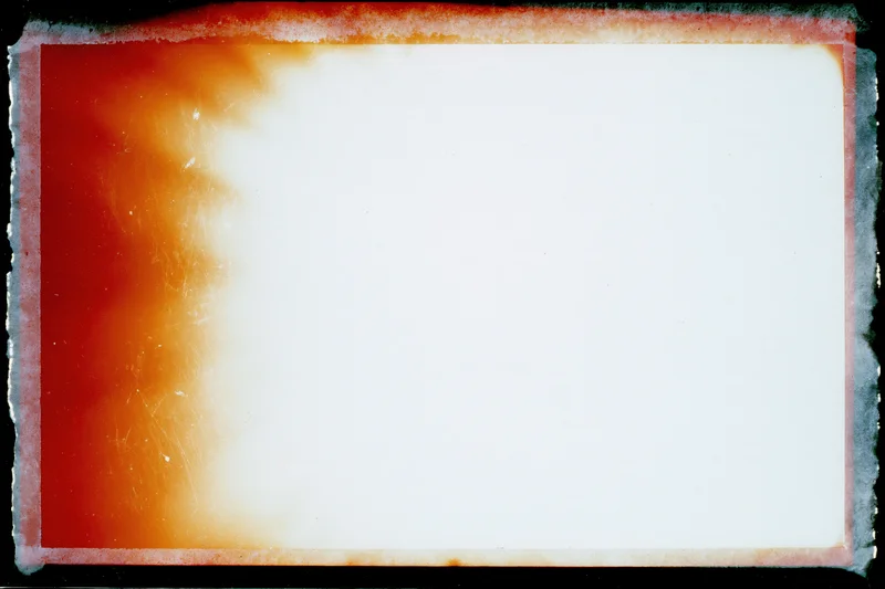 Blank analog film frame with heavy light leak and warm color gradient along the left edge