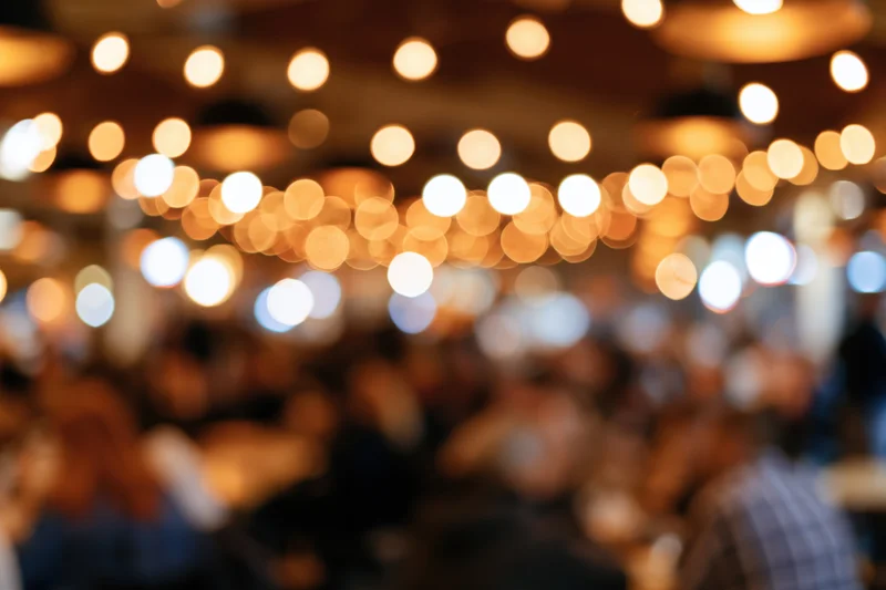 Blurred view of people dining and socializing in a warmly lit restaurant or bar at night