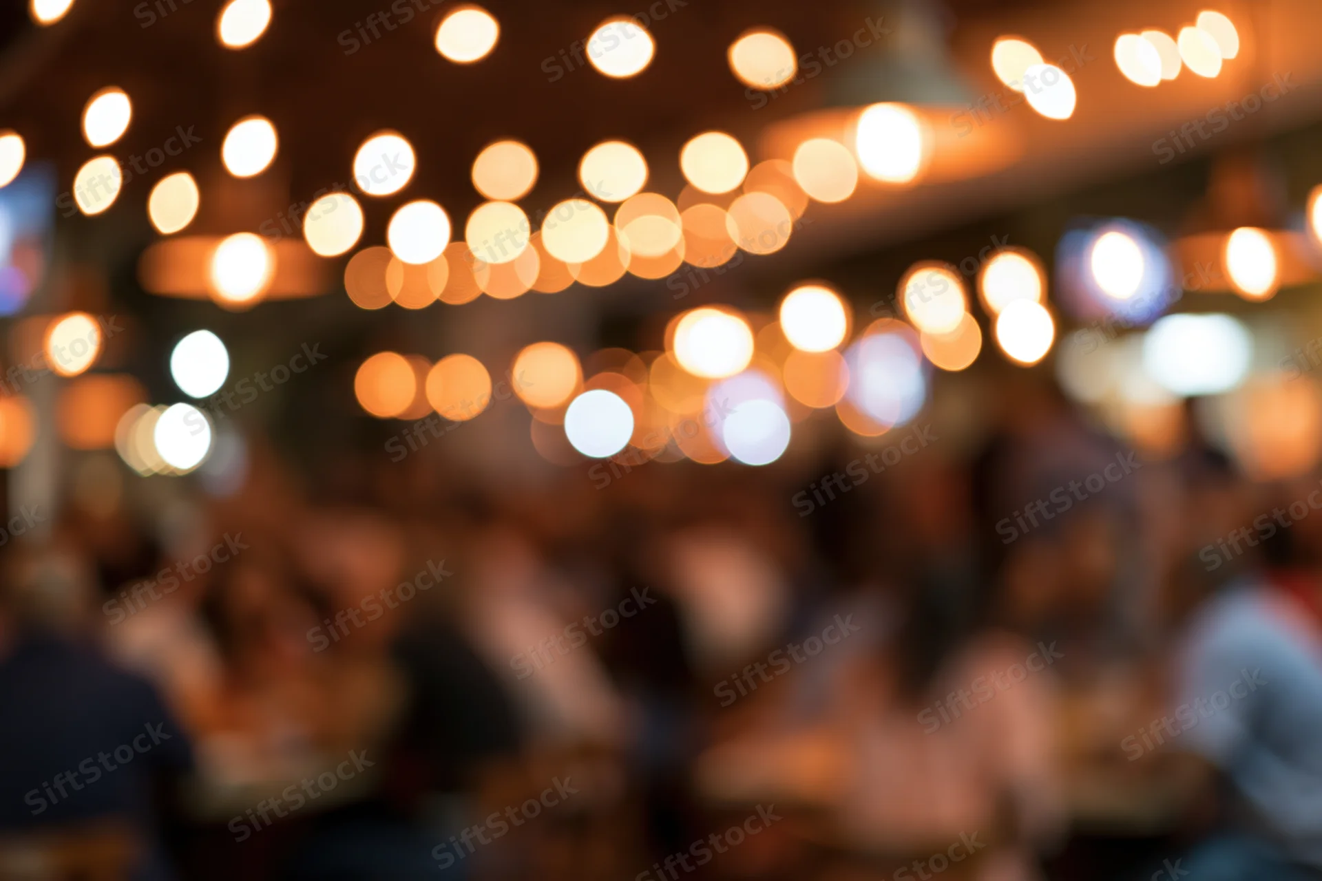 Blurred view of people dining and socializing in a warmly lit restaurant or bar at night