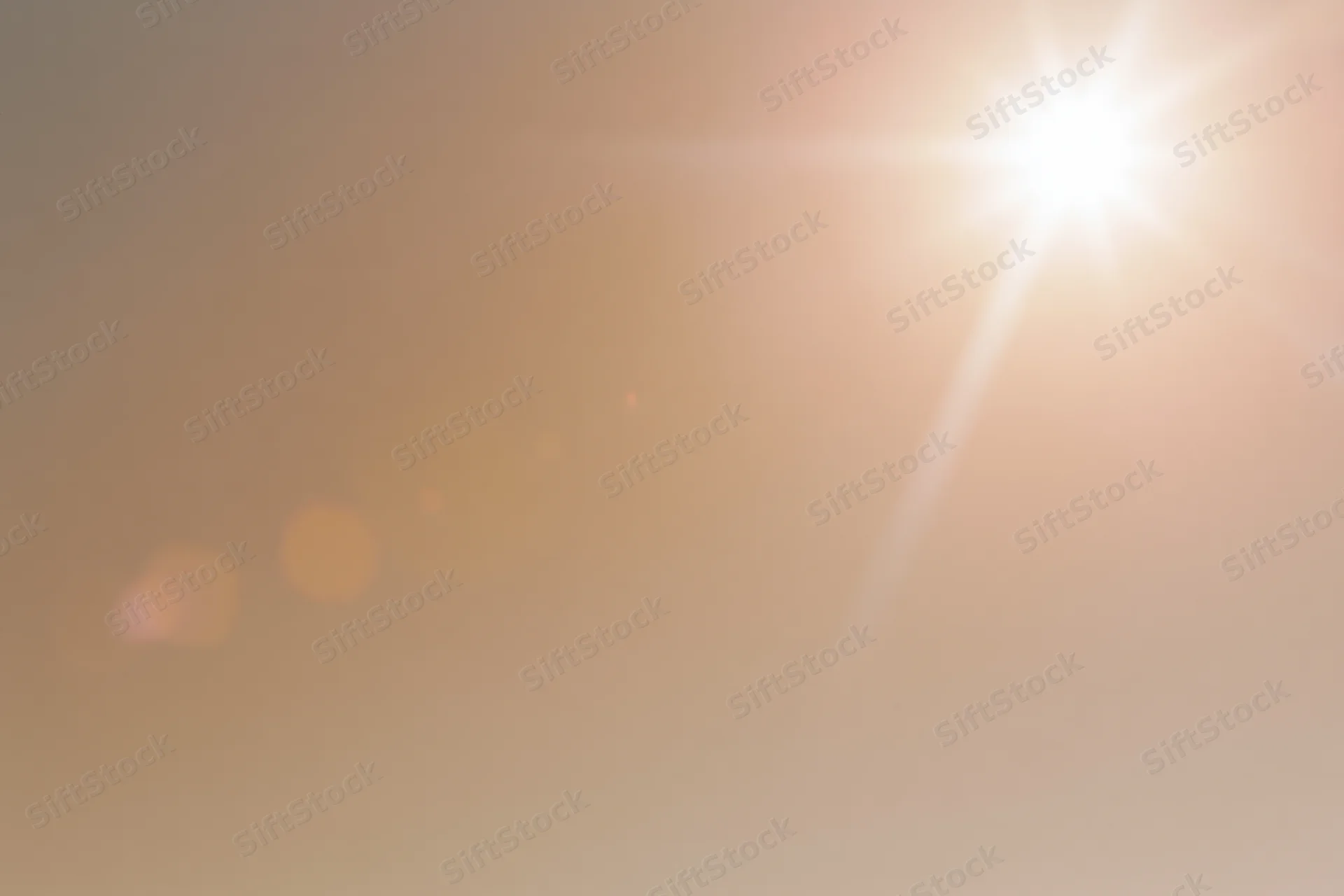 Bright midday sun bursting from upper right corner against hazy sky