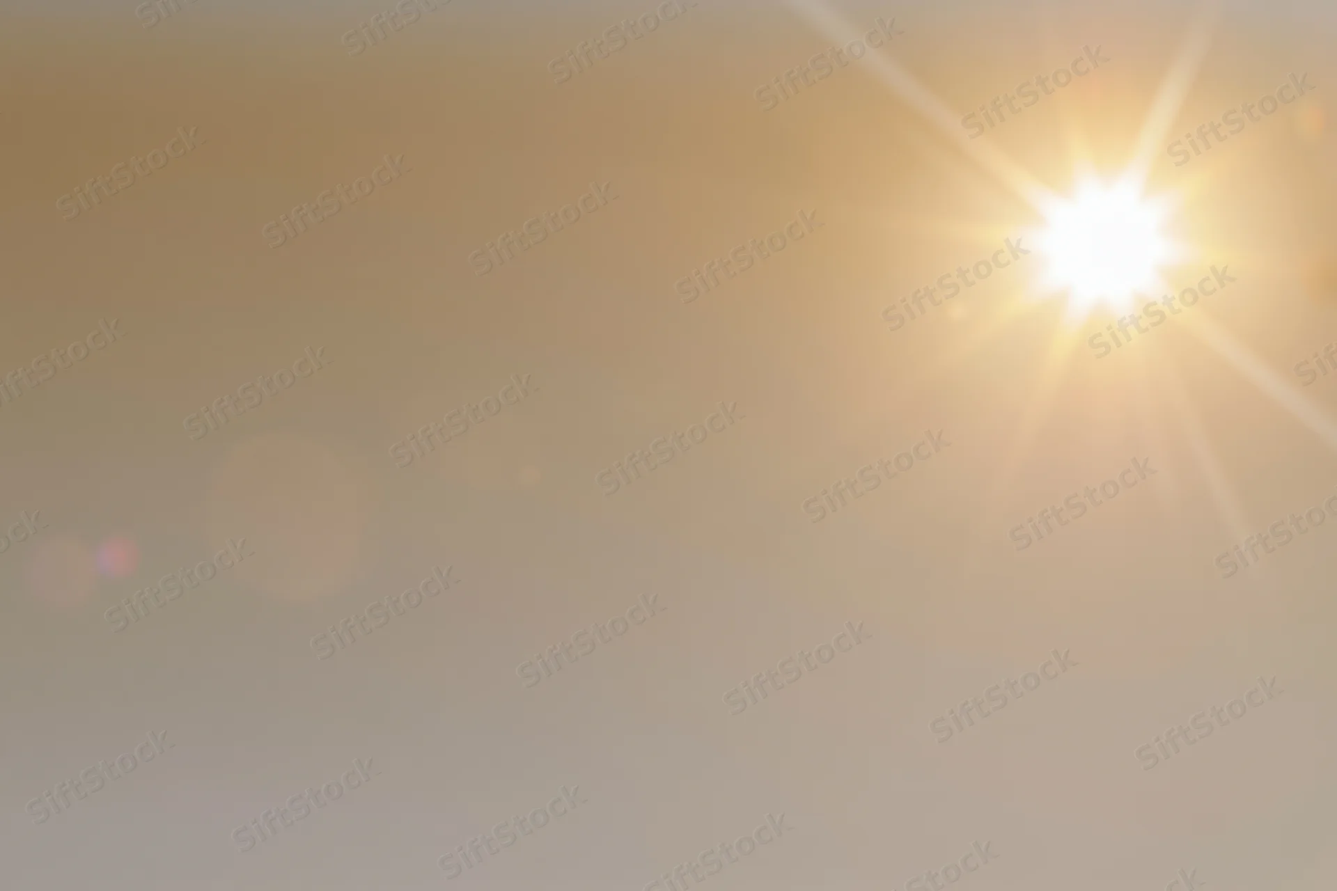Bright midday sun bursting from the upper right corner against a hazy golden sky