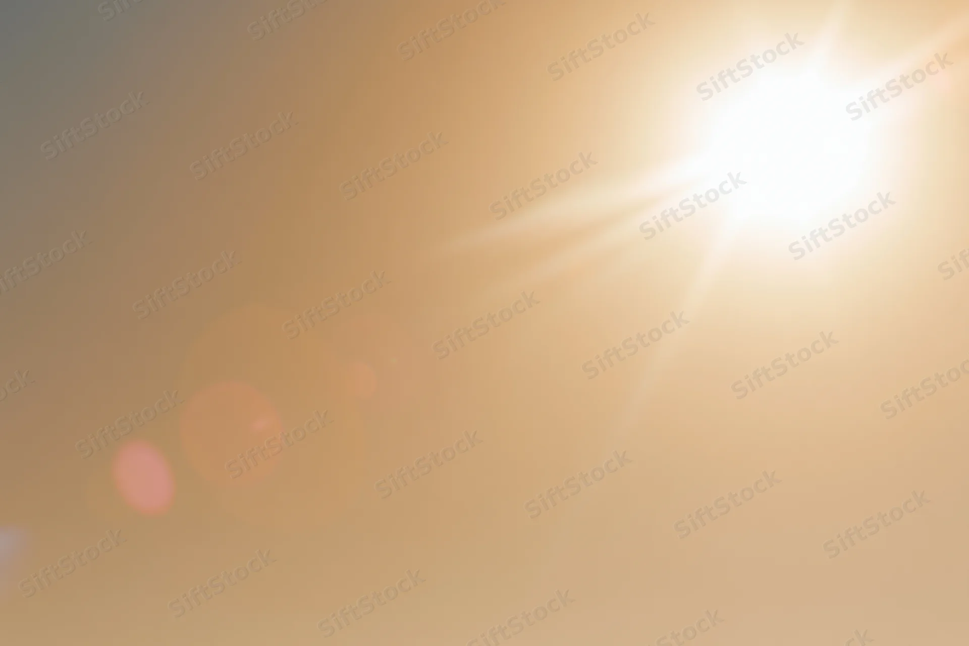 Bright midday sun bursting from upper right corner against hazy sky with lens flare and bokeh highlights