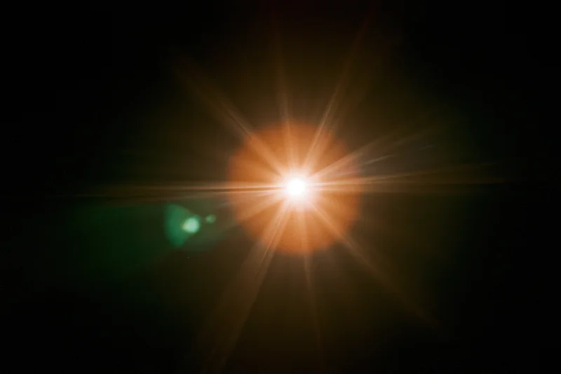 Bright point light source glowing with starburst flare against black background
