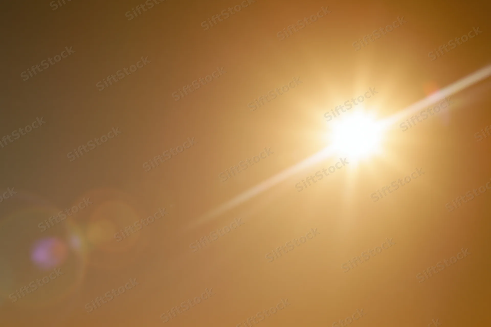Bright sun blazing in a hazy sky with lens flare and bokeh effects