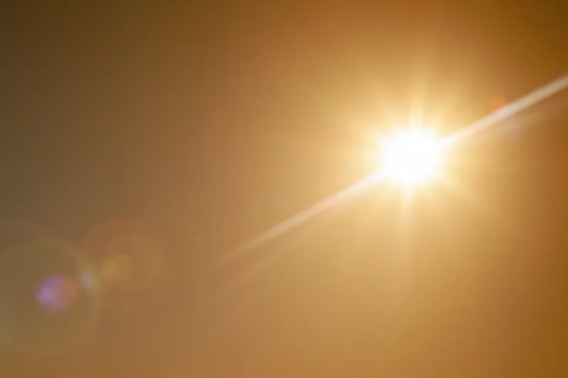 Bright sun blazing in a hazy sky with lens flare and bokeh effects