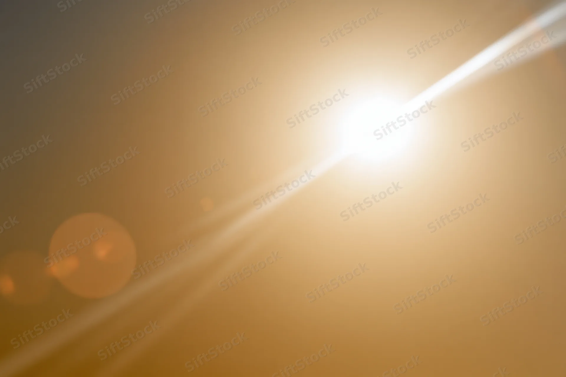 Bright sun shining in hazy sky with lens flare and bokeh highlights