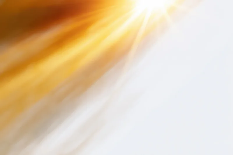 Bright sunlight rays bursting from the upper-left corner across a white gradient background
