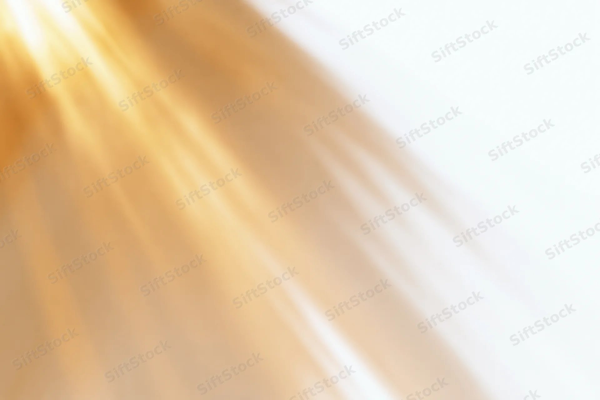 Bright golden sunlight rays radiating diagonally across a white background with soft blur and copyspace