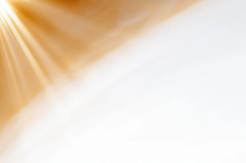 Bright sunlight rays bursting from upper-left corner across white background