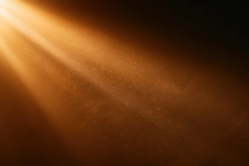 Golden light rays streaming through dust particles in a dark room