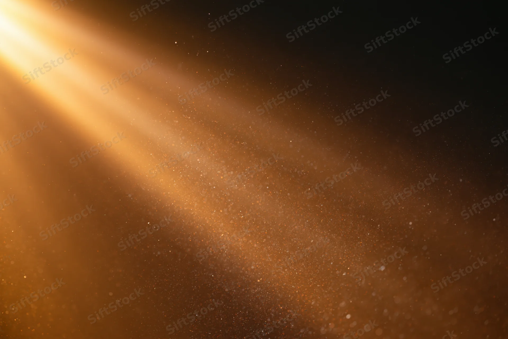 Golden light rays illuminating floating dust particles in a dark space