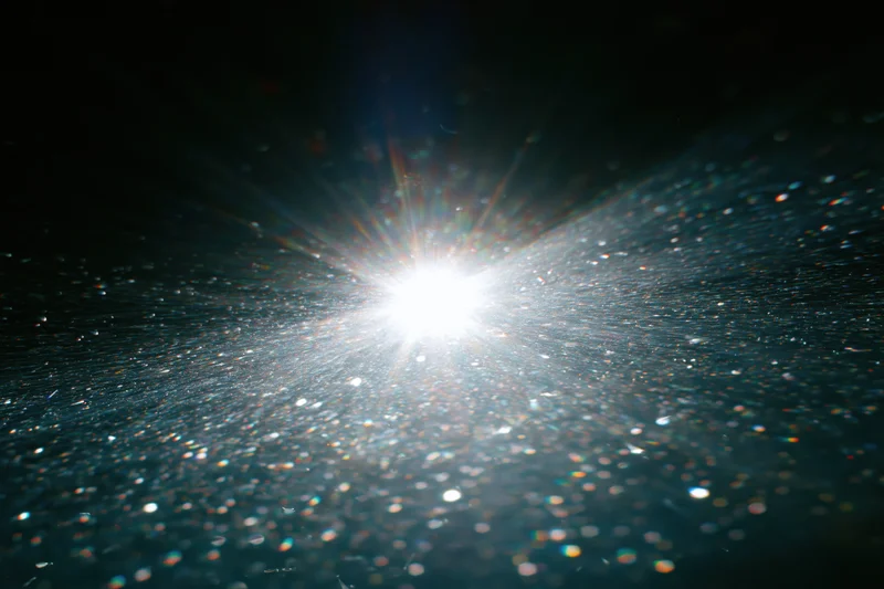Bright white light bursting underwater with sparkling particles and lens flare
