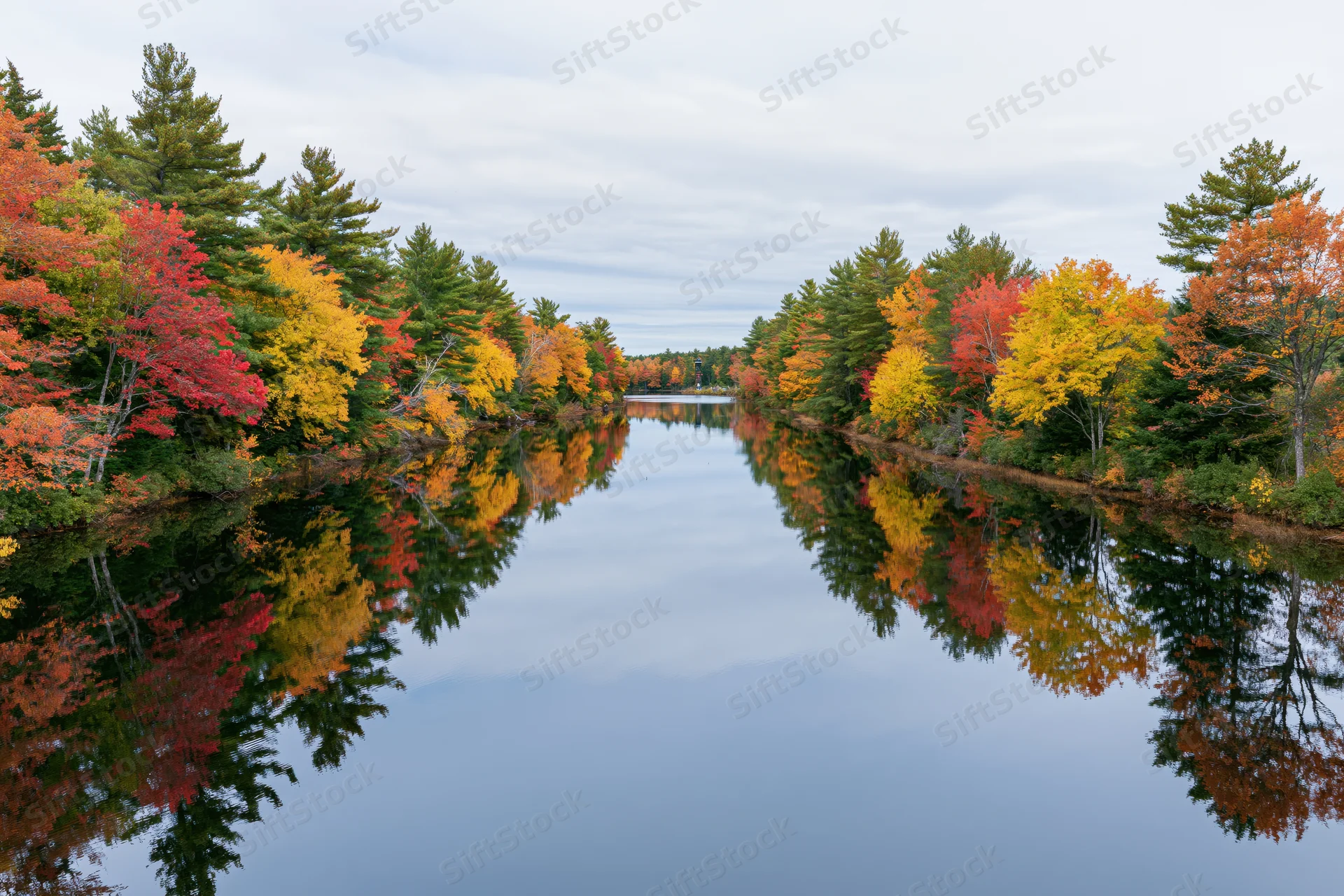 Calm river reflecting autumn foliage along its banks in New England