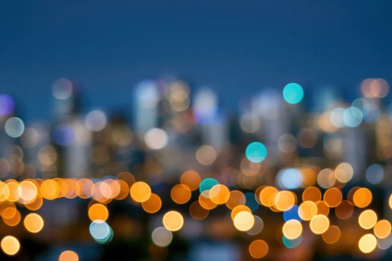 Blurred city skyline at night with bokeh lights in foreground