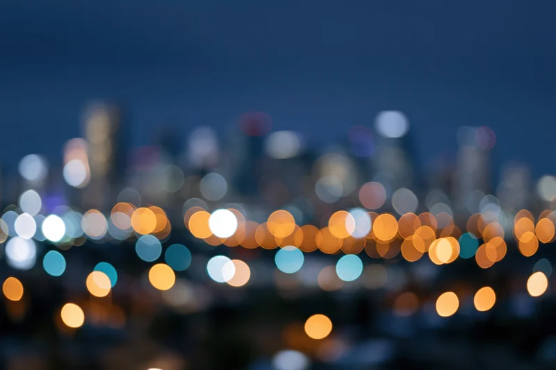 Blurred city skyline at night with bokeh lights in warm and cool tones