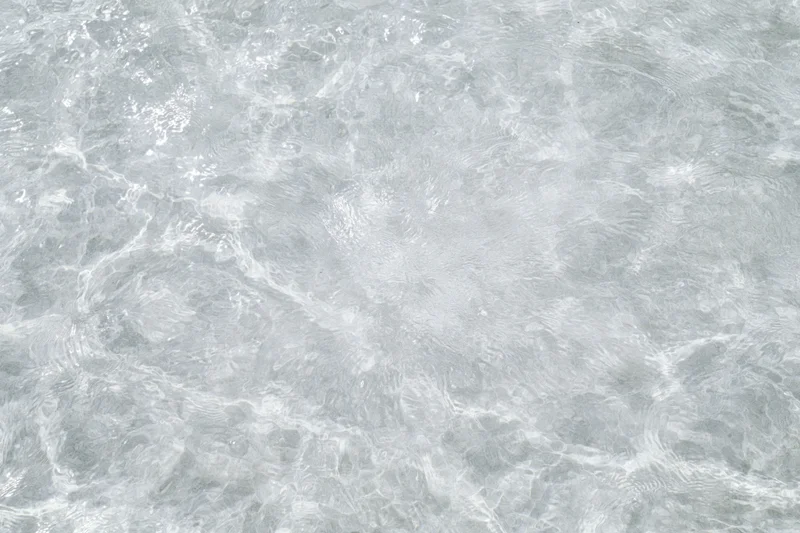 Clear shallow water surface with small ripples and light reflections viewed from above