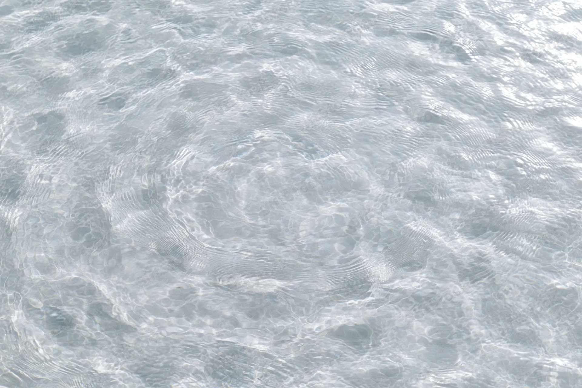 Clear shallow water surface with small ripples and light reflections viewed from above