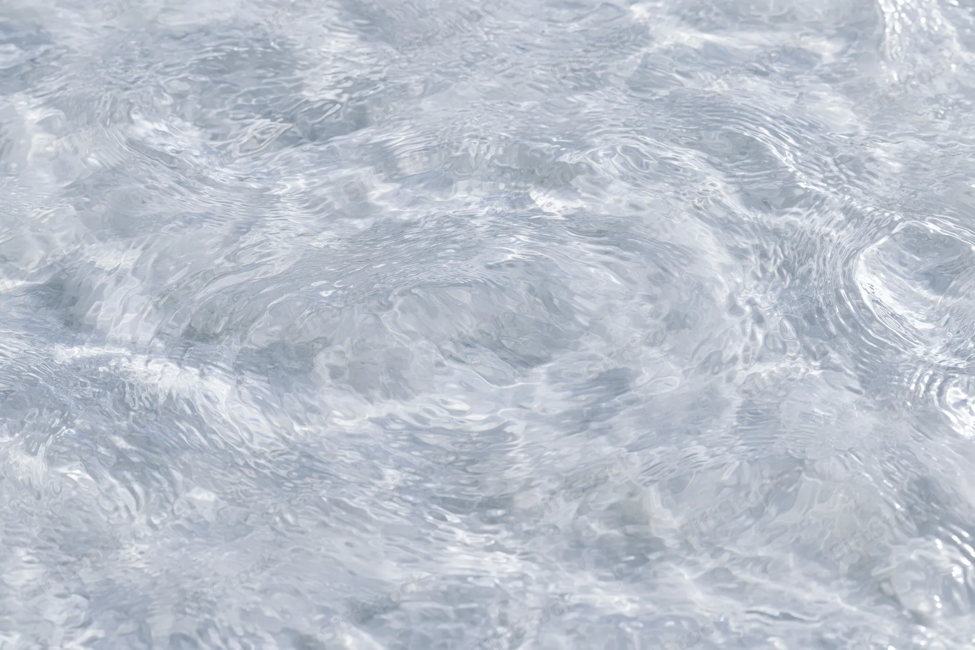 Clear shallow water surface with small ripples and light reflections viewed from above