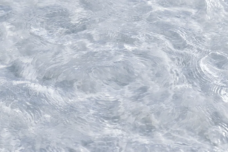 Clear shallow water surface with small ripples and light reflections viewed from above