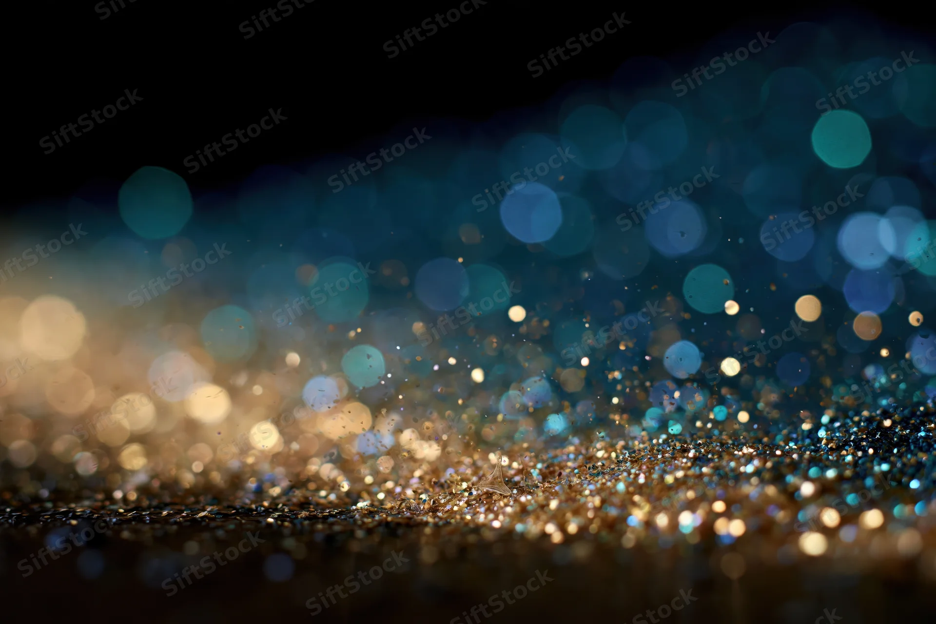 Scattered glitter with bokeh lights on dark surface, creating abstract sparkle effect