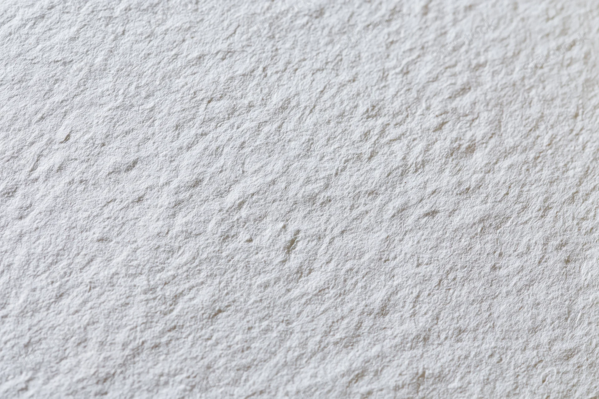 Close-up flat lay of a blank white watercolor paper sheet showing textured surface