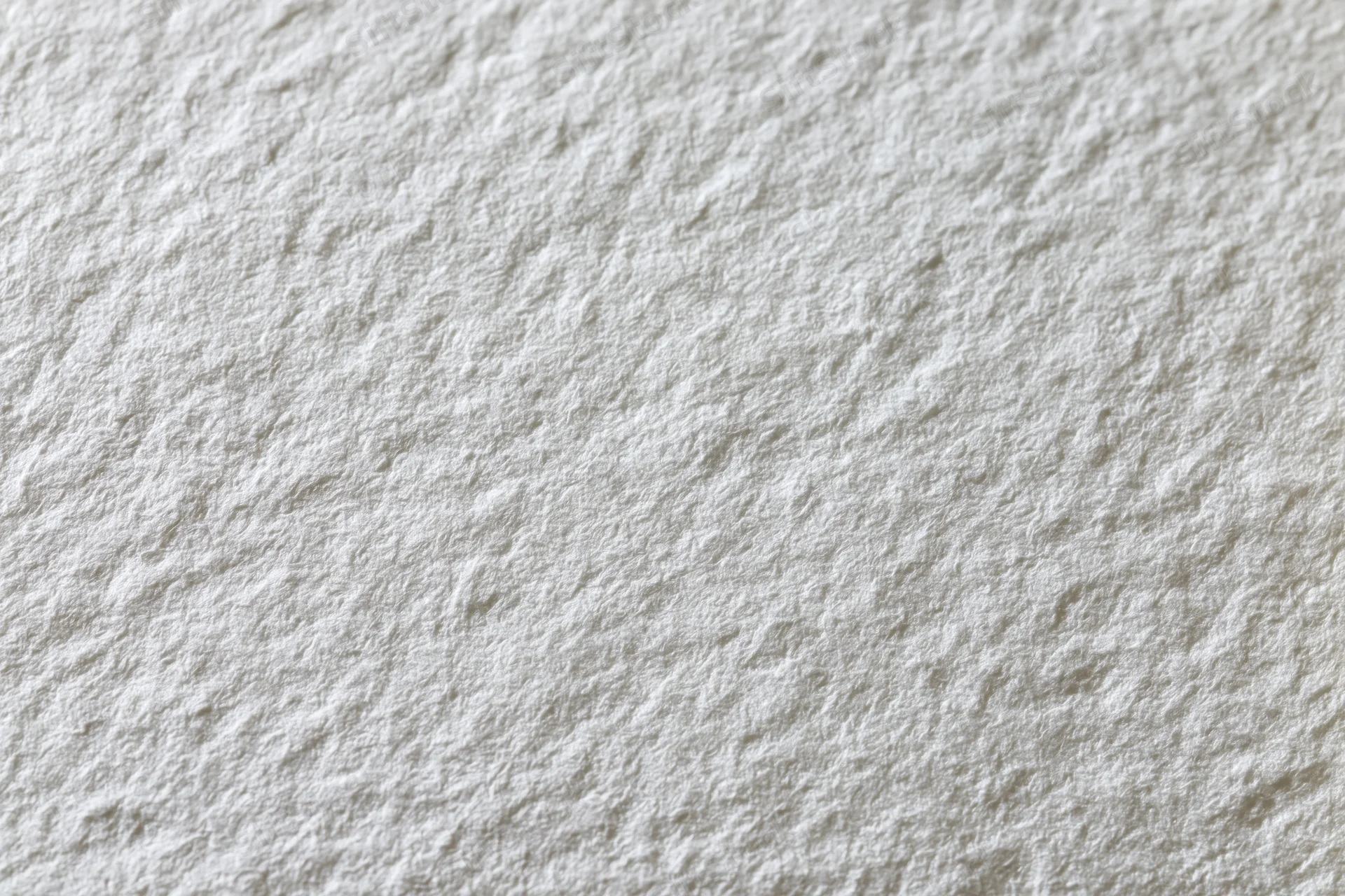 Close-up flat lay of a blank white watercolor paper sheet showing its textured surface