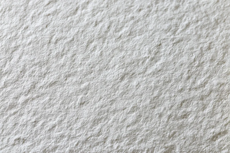 Close-up flat lay of a blank white watercolor paper sheet showing its textured surface