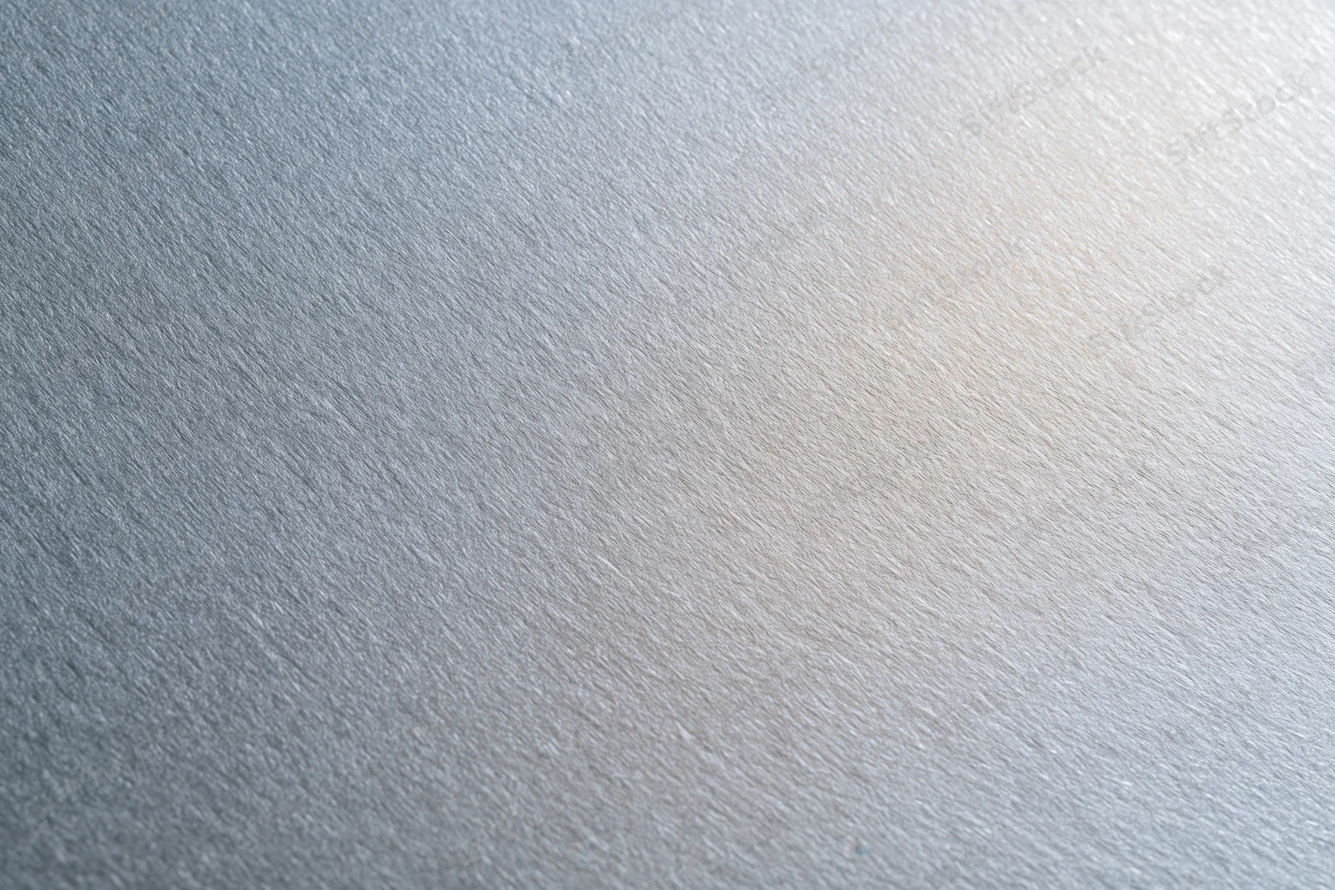 Close-up flat lay of a brushed aluminum surface with frosted texture and subtle light gradient