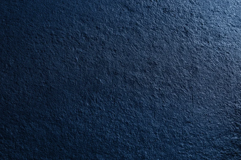 Close-up flat lay of dark navy blue textured concrete surface
