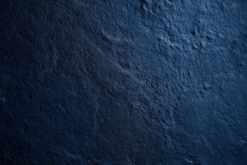Dark navy blue textured concrete surface in close-up flat lay view