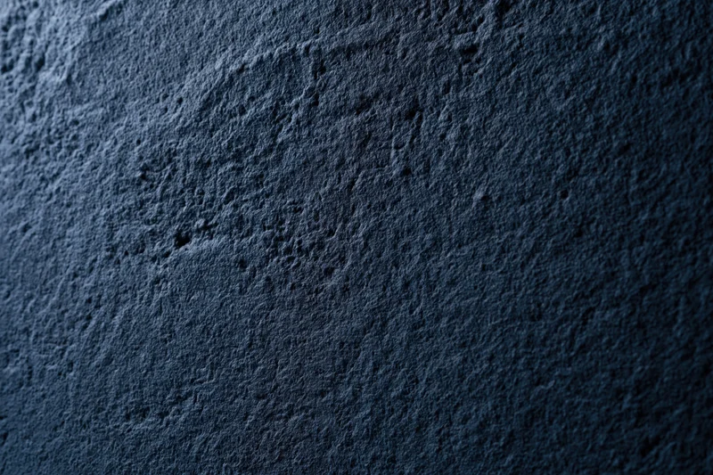 Close-up of dark navy blue textured concrete surface in flat lay arrangement