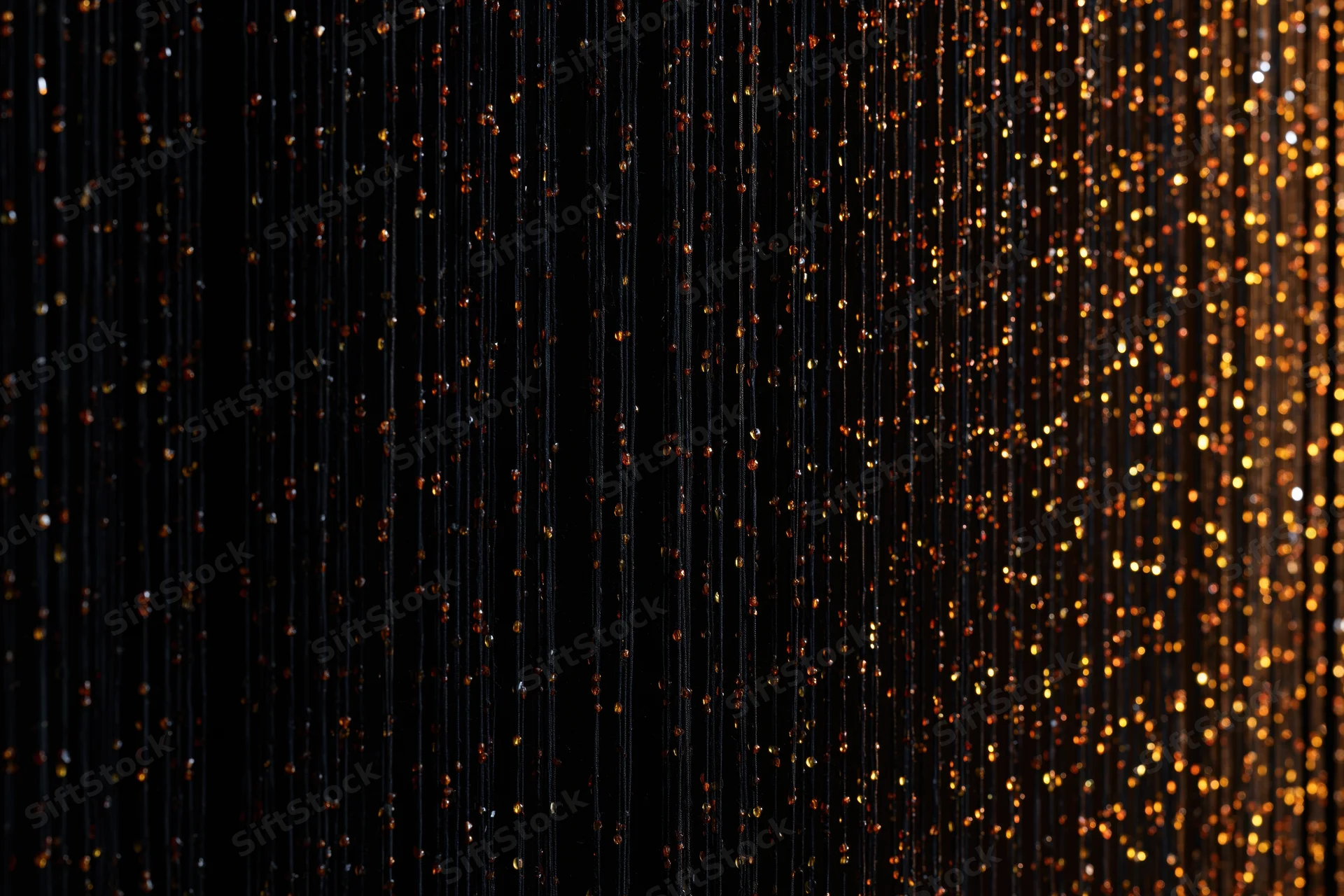 Vertical strands of glittering sequins forming a decorative curtain against a dark background