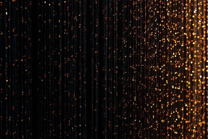Vertical strands of glittering sequins forming a decorative curtain against a dark background