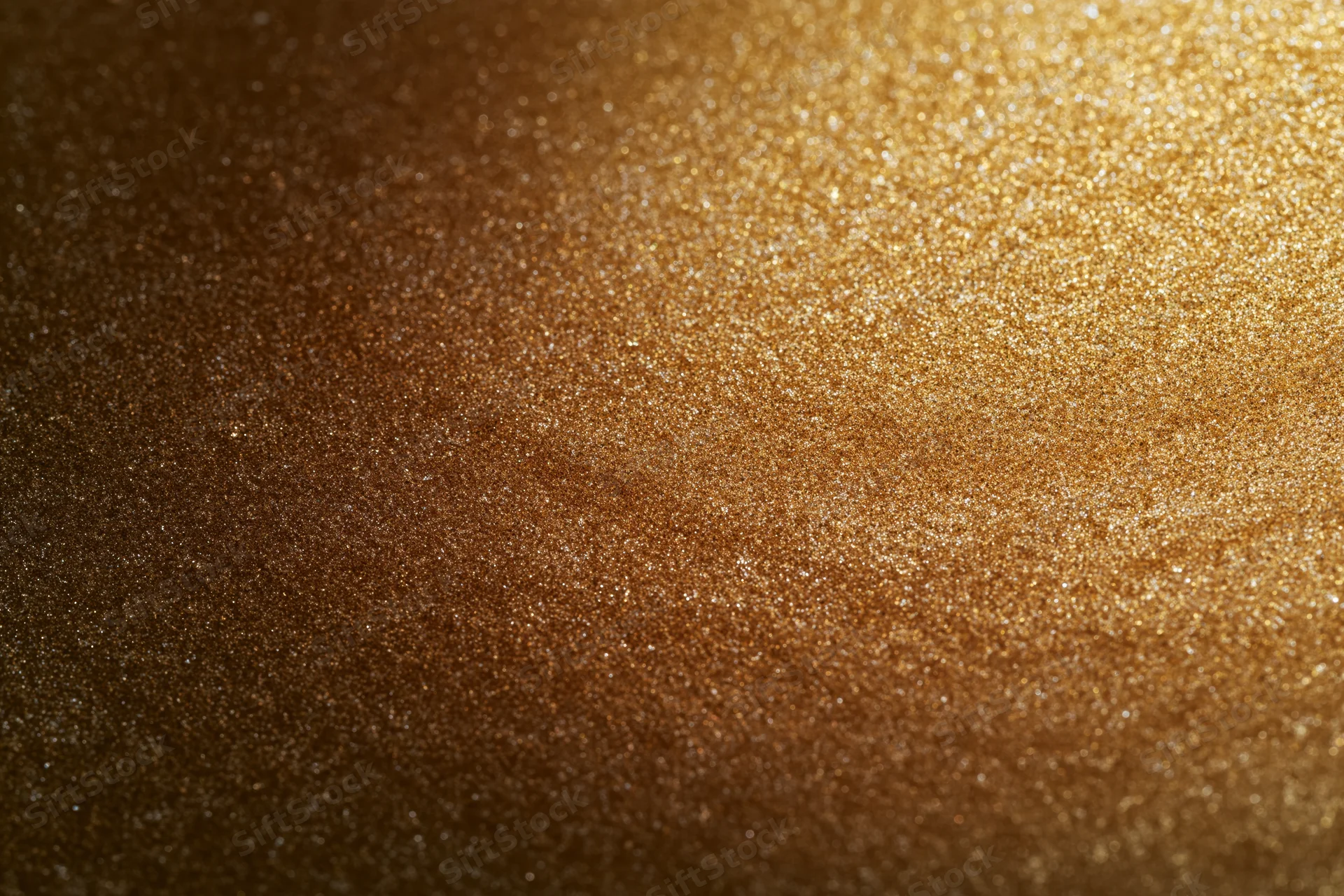 Close-up of a gold glitter-coated surface with sparkling texture and gradient lighting