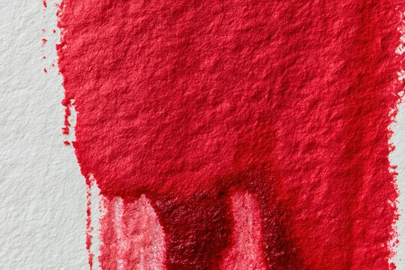 Hand-painted red watercolor wash on textured paper with visible brush strokes and color bleed