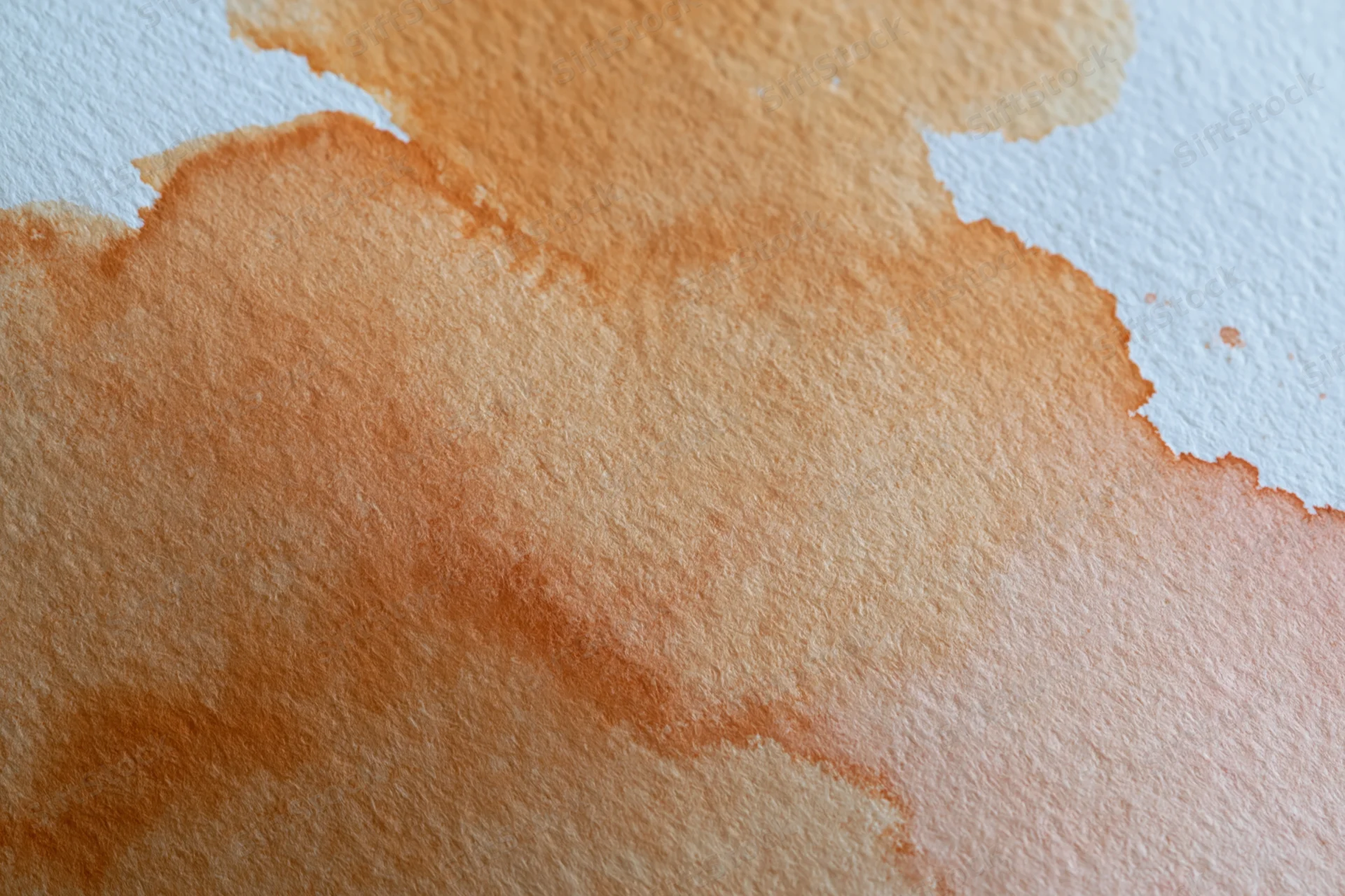 Close-up of a hand-painted watercolor wash on textured paper with soft orange and brown gradients and white edges