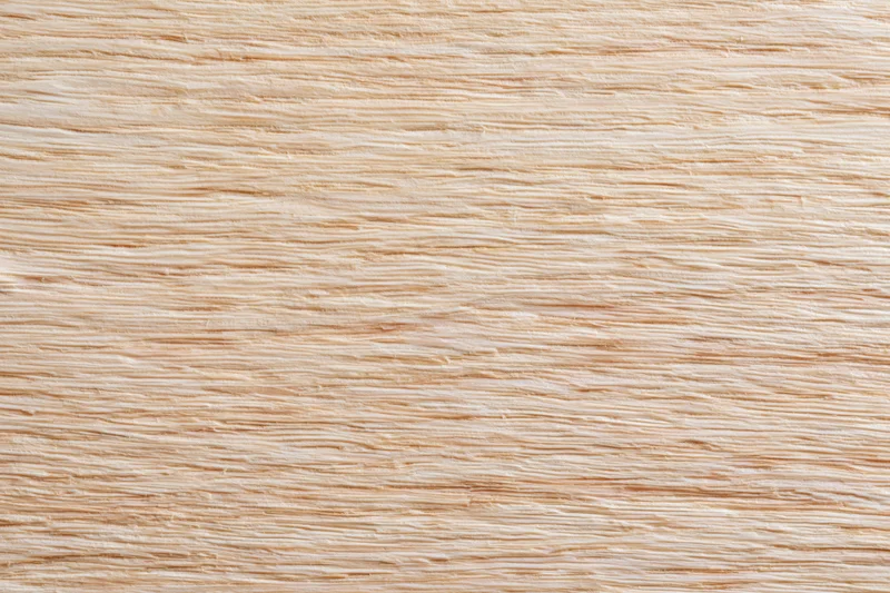 Close-up flat lay of a light blonde wood surface with fine straight grain pattern