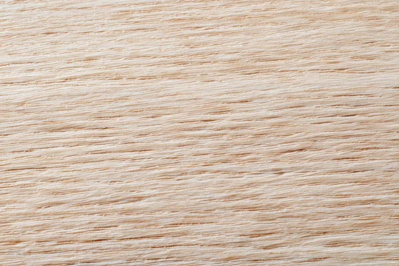 Close-up flat lay of a light blonde wood surface with fine straight grain pattern