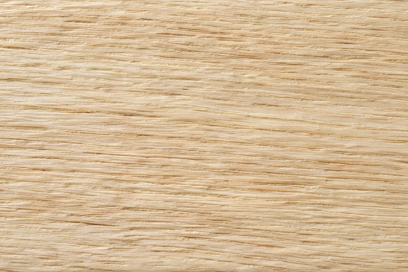 Close-up flat lay of a light blonde wood surface with fine straight grain pattern