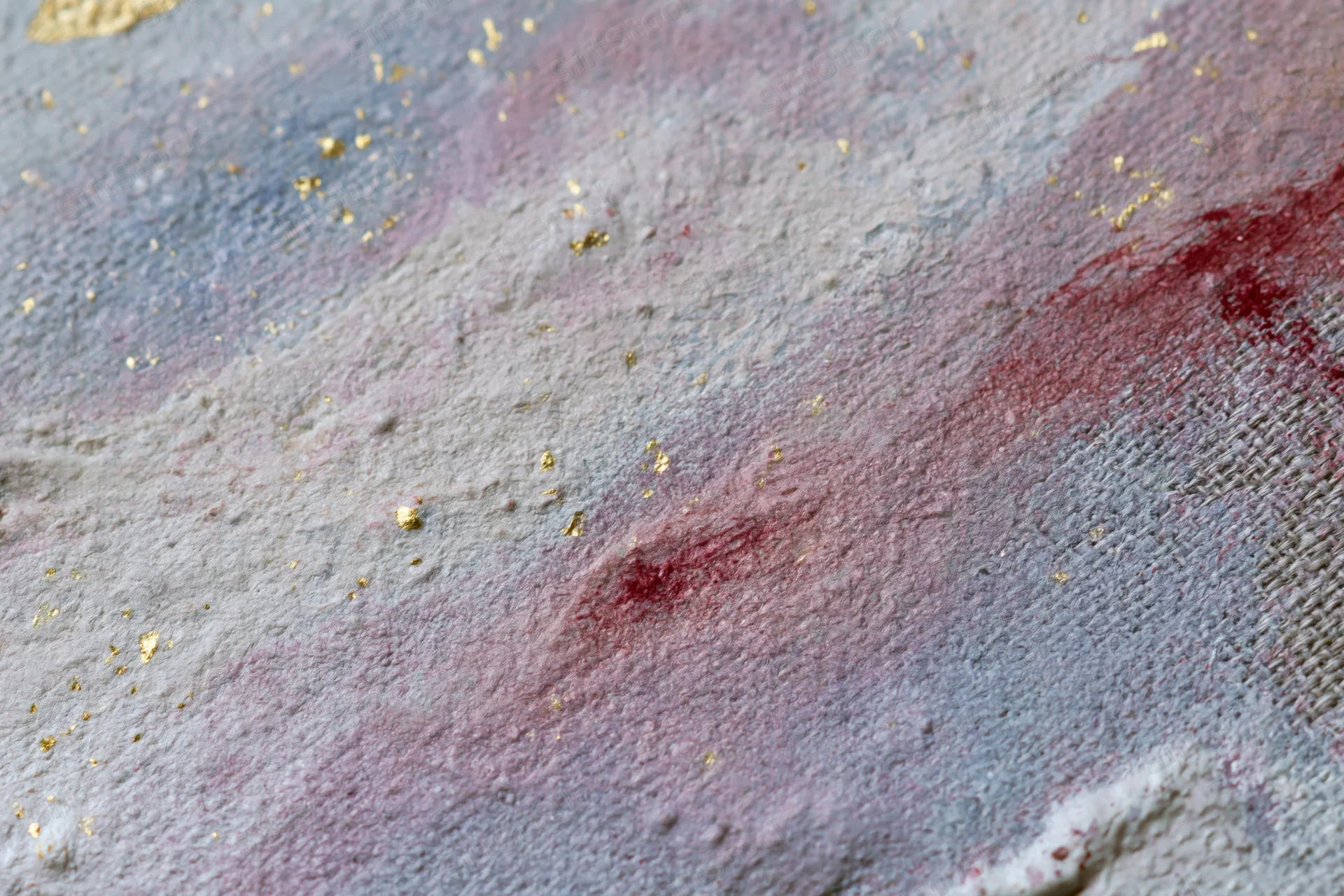 Close-up of layered abstract paint on linen canvas with gold speckles and blended red blue purple hues