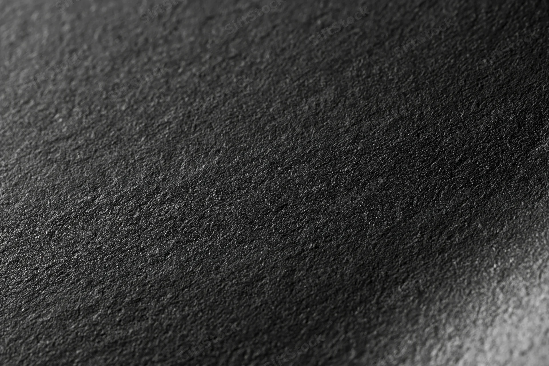 Close-up flat lay of a matte black textured surface filling the frame