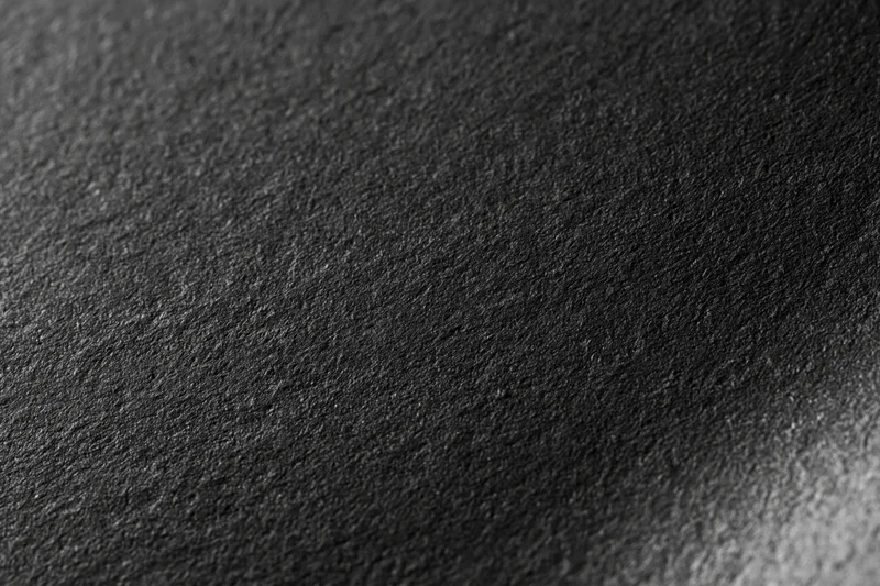 Close-up flat lay of a matte black textured surface filling the frame