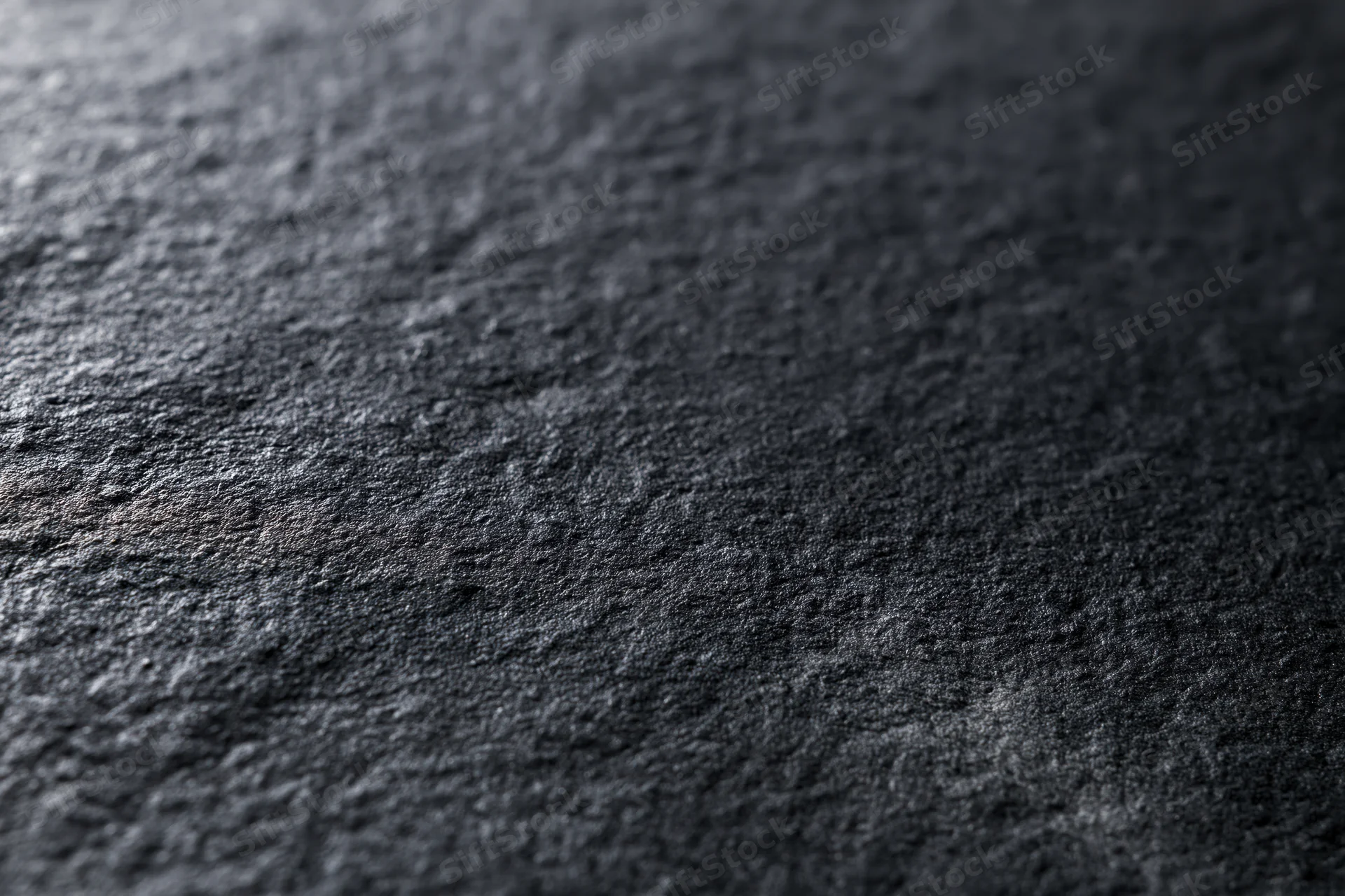 Matte black textured surface in close-up flat lay filling frame