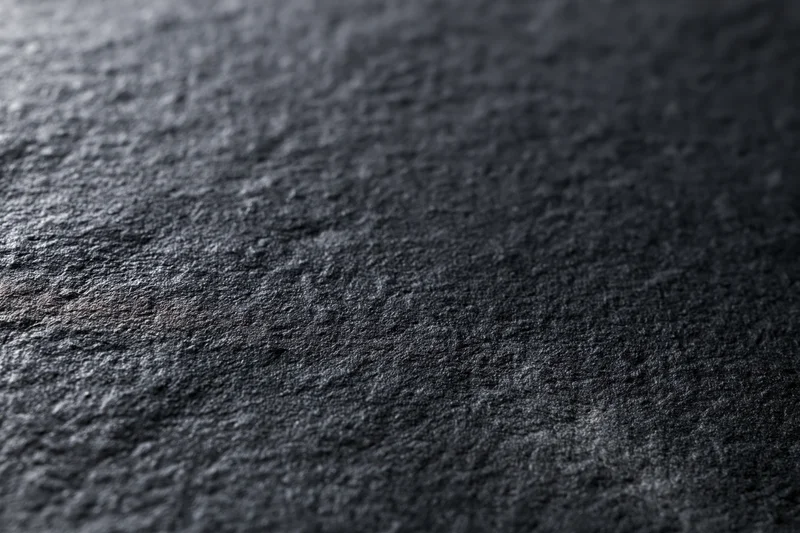 Matte black textured surface in close-up flat lay filling frame