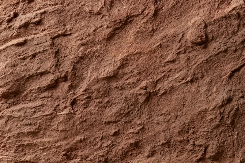 Close-up of rough stucco wall surface with textured finish