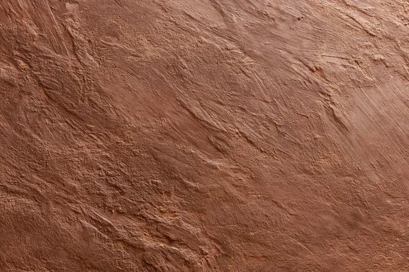 Close-up of rough stucco wall surface with visible texture and grain