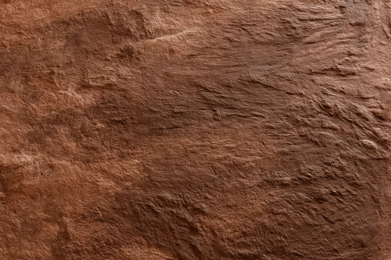 Close-up of rough stucco wall surface with textured brown finish