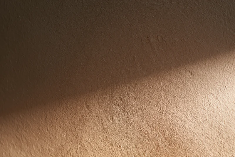 Close-up of a smooth plastered wall surface with soft lighting and shadow gradient in an indoor setting