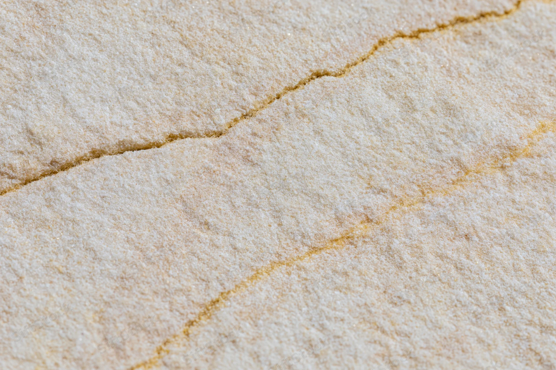 Close-up of a smooth sandstone surface showing natural cracks and layered texture